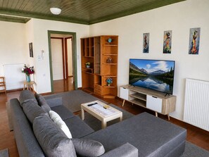 Un salon avec un canapé, un téléviseur, des étagères en bois et des œuvres d’art accrochées au mur.