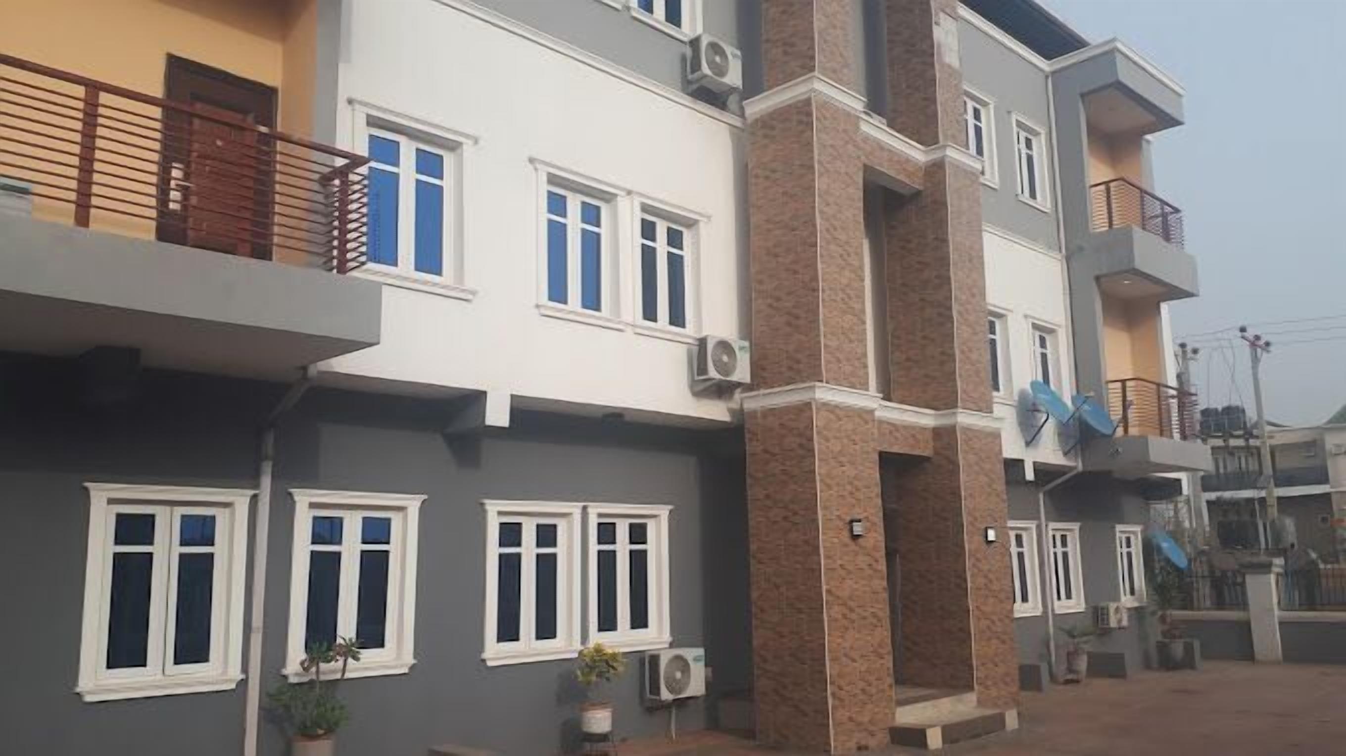 Un edificio residencial de varios pisos con balcones, unidades de aire acondicionado y fachada de ladrillo.