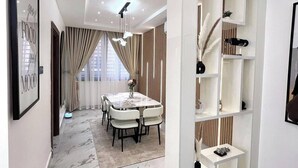 A modern dining area with a marble floor, a round table, and white chairs. - Winnie Host and Homes (Abuja)