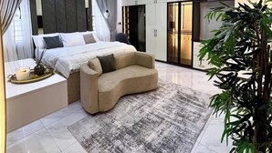A modern bedroom with a bed, a sofa, a large mirror, and a plant. - Winnie Host and Homes (Abuja)