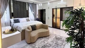 A modern bedroom with a bed, a sofa, a large mirror, and a plant.