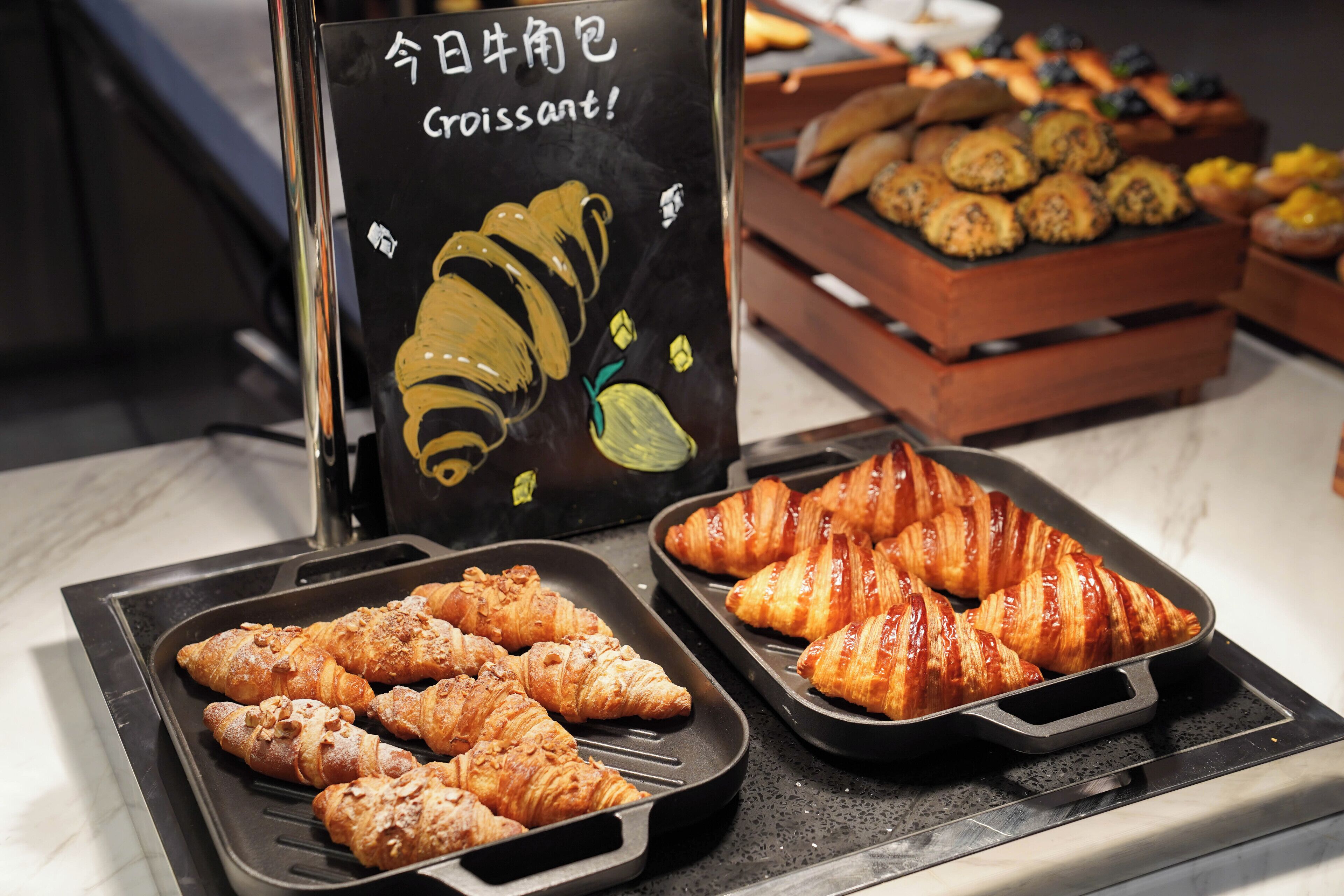 Une présentation de croissants et d’autres viennoiseries sur des plateaux.