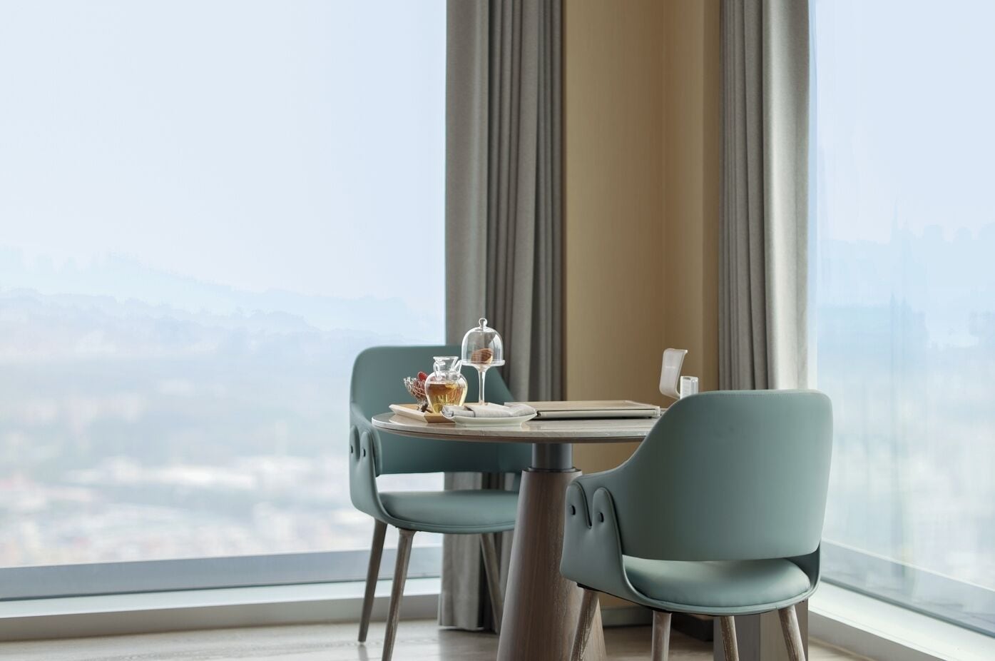 Un'area pranzo con un tavolo apparecchiato per due persone, due sedie, un bicchiere di vino, una bottiglia di liquore e un piccolo oggetto decorativo.