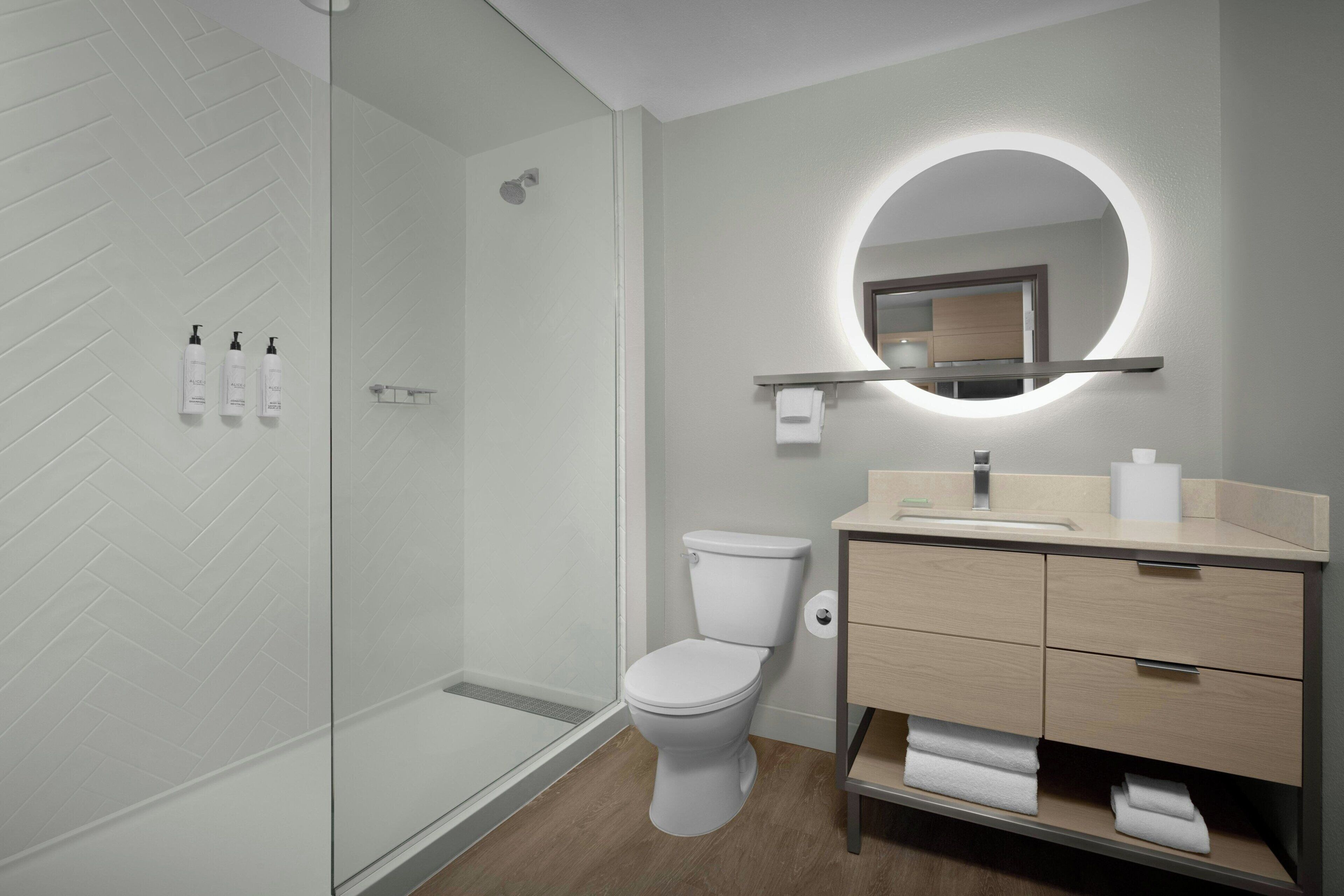 A modern bathroom with a glass shower enclosure, a toilet, and a vanity with a mirror.