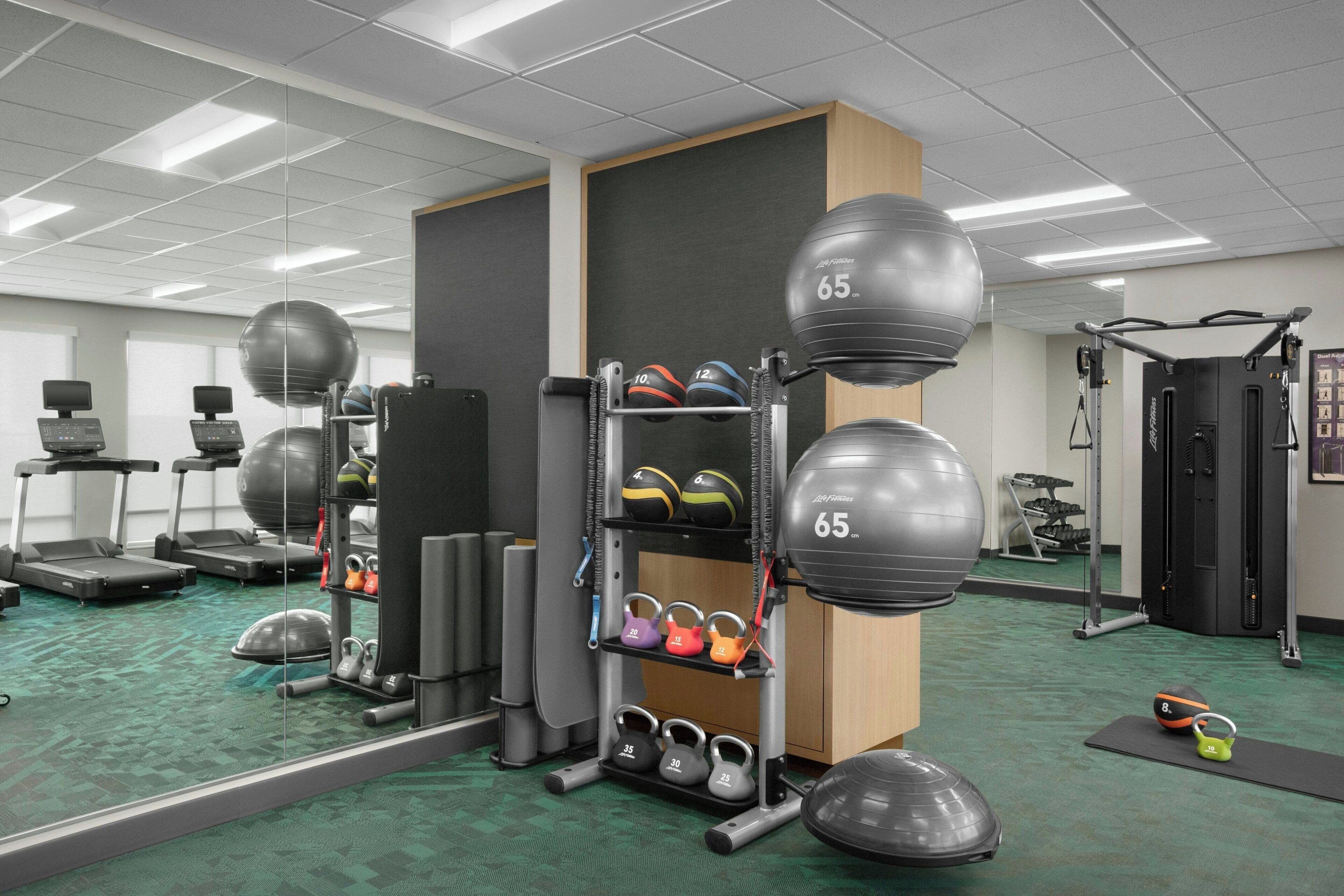 A gym with treadmills, exercise balls, and weightlifting equipment.