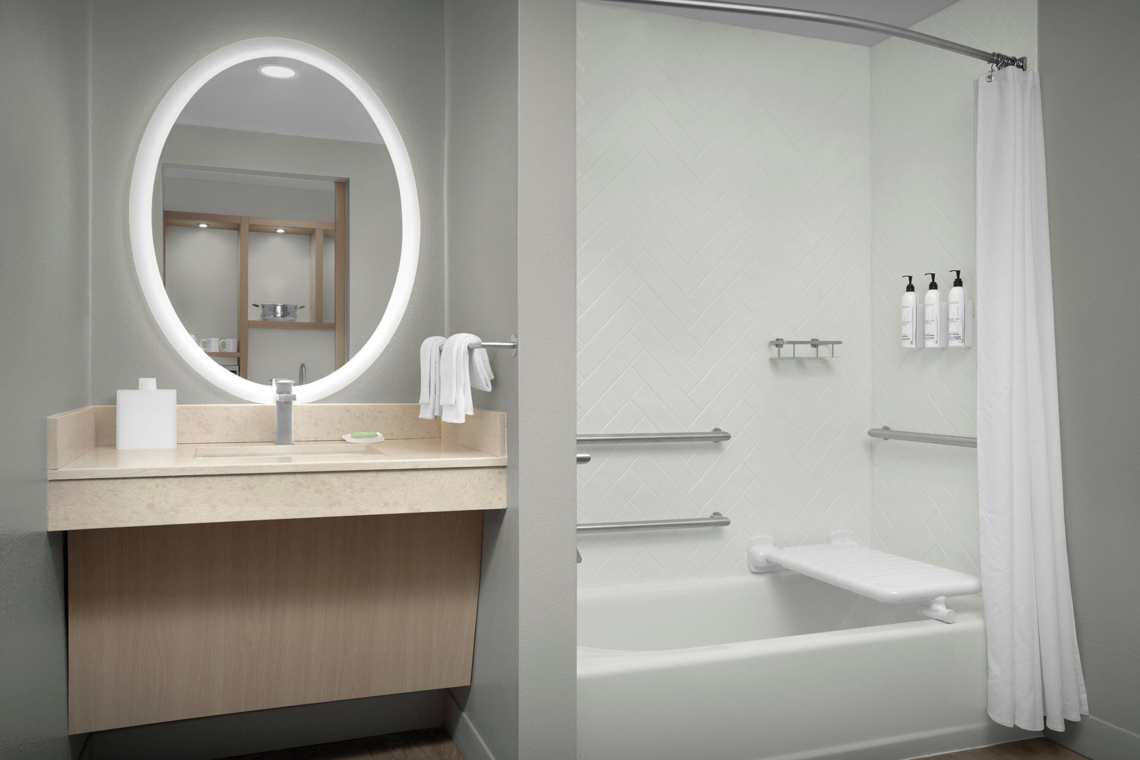 A modern bathroom with a vanity, a mirror, a bathtub, and a shower curtain.