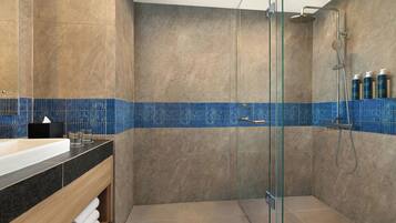 Ein modernes Badezimmer mit einer gläsernen Dusche, einem Holzwaschtisch und einer blauen Fliesenrückwand.