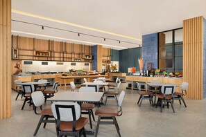 A modern restaurant with wooden paneling, a central island with food displays, and multiple seating areas. - Four Points By Sheraton Pontianak (Pontianak)