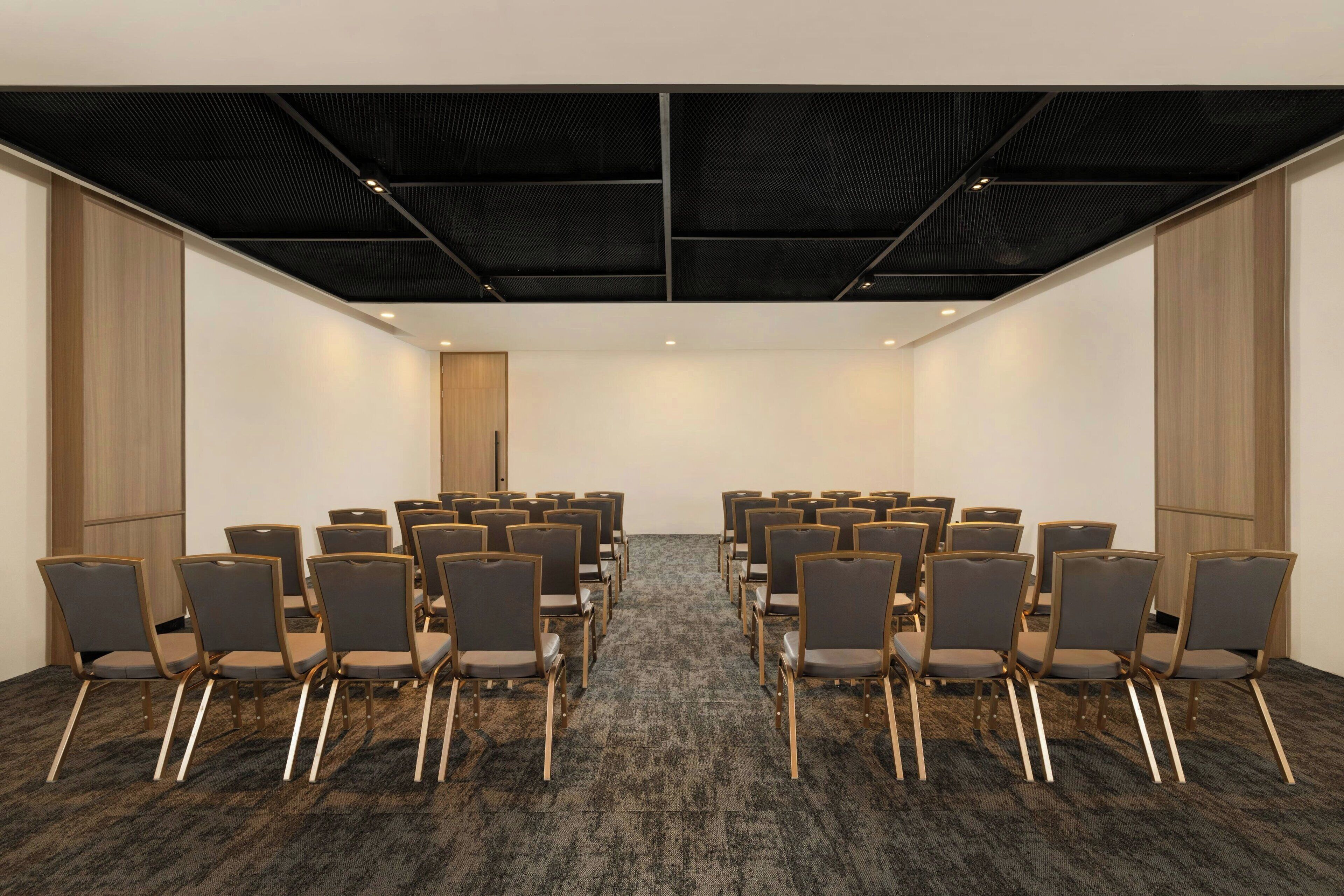 Ein Konferenzraum mit Reihen von Stühlen, Teppichboden und einer Holzvertäfelung.