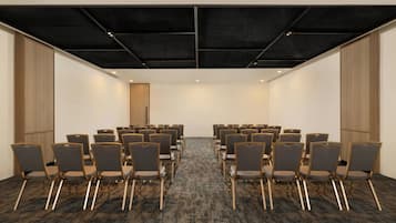 A conference room with rows of chairs, a carpeted floor, and a wooden panel wall.