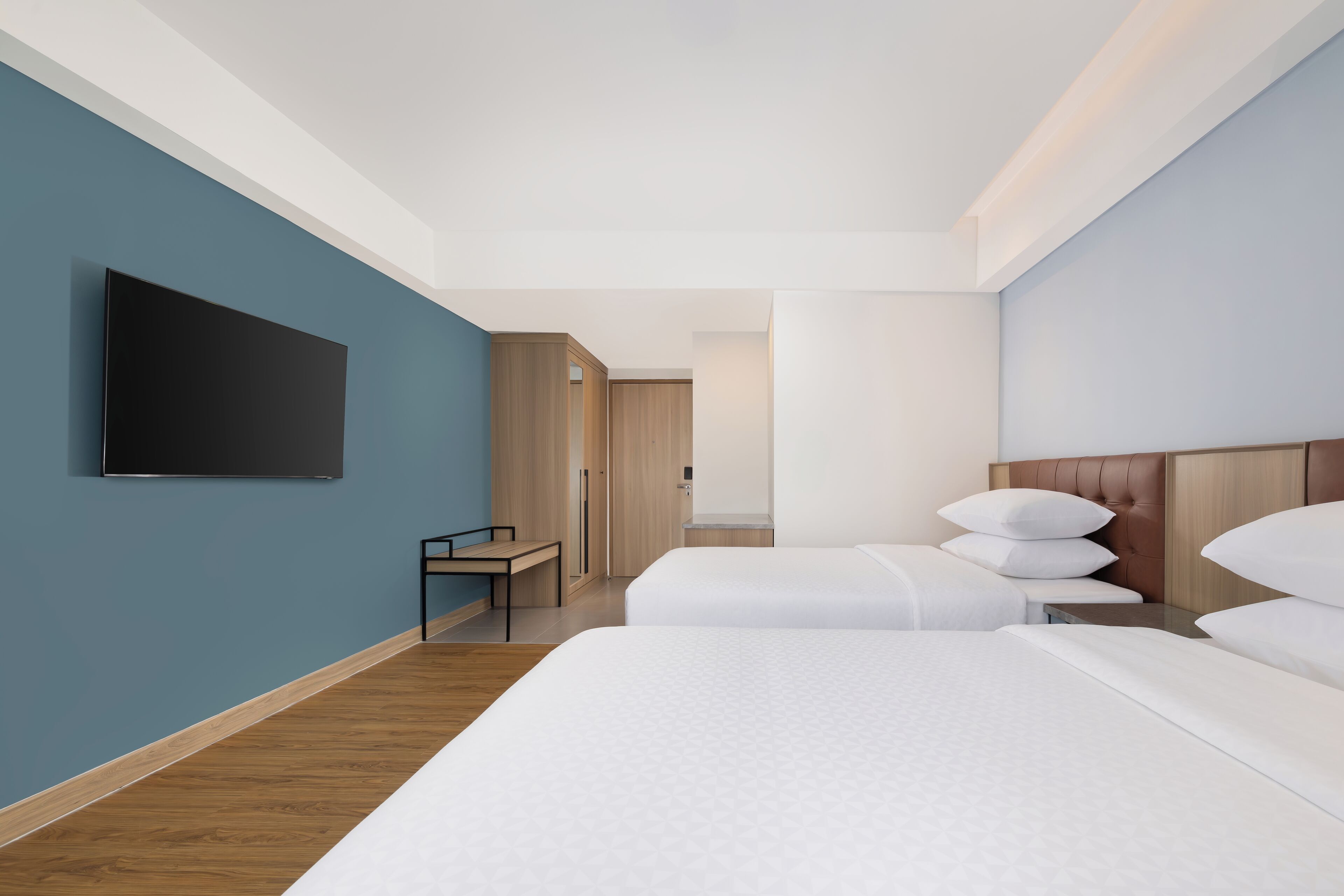 Een moderne hotelkamer met twee bedden, een flatscreen-tv, een bureau en een kledingkast.