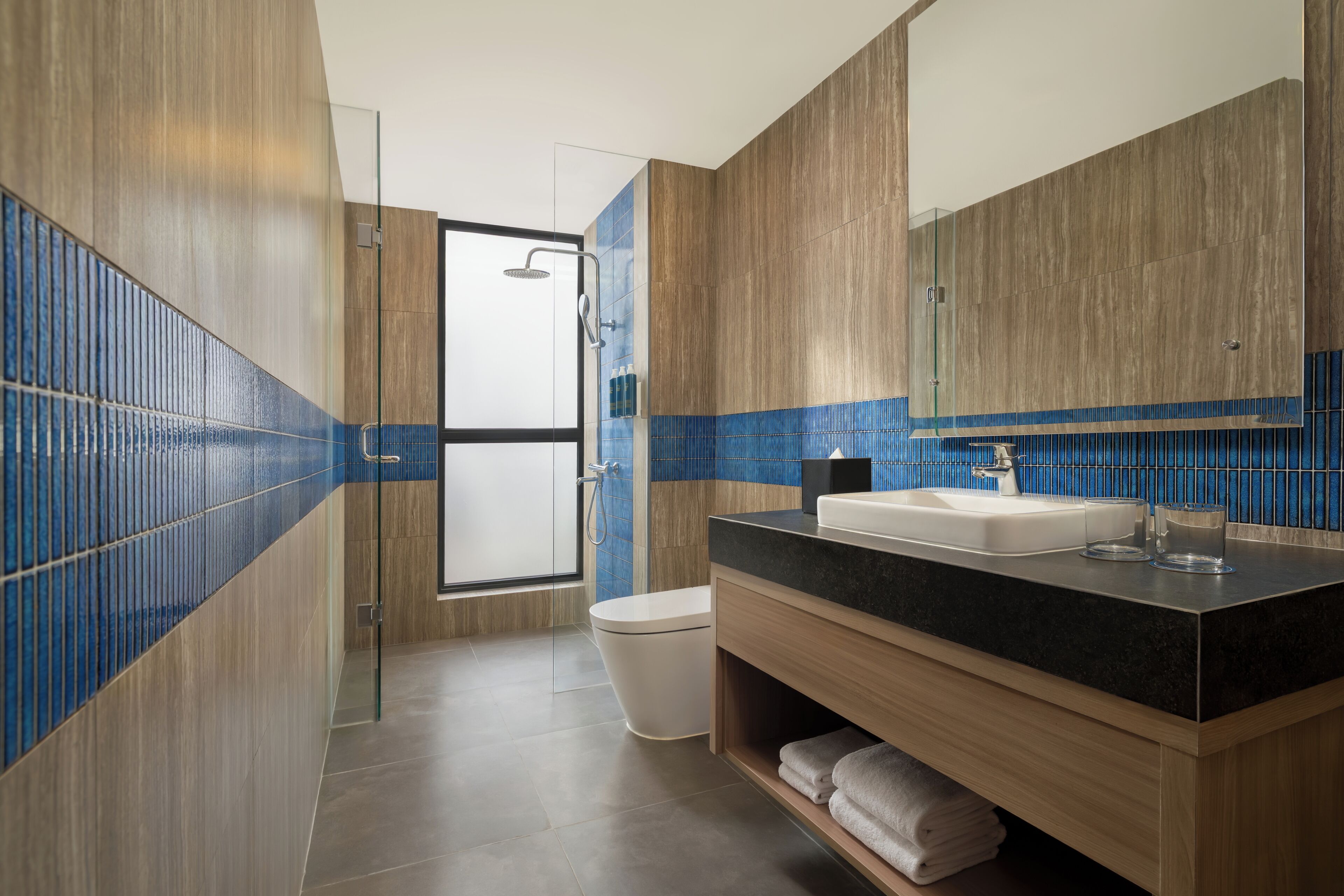 A modern bathroom with a shower, toilet, and sink.