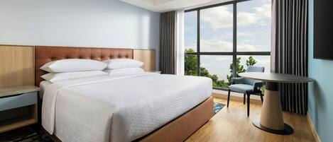 Habitación de hotel con una cama grande, un escritorio, una silla y una ventana con vistas.