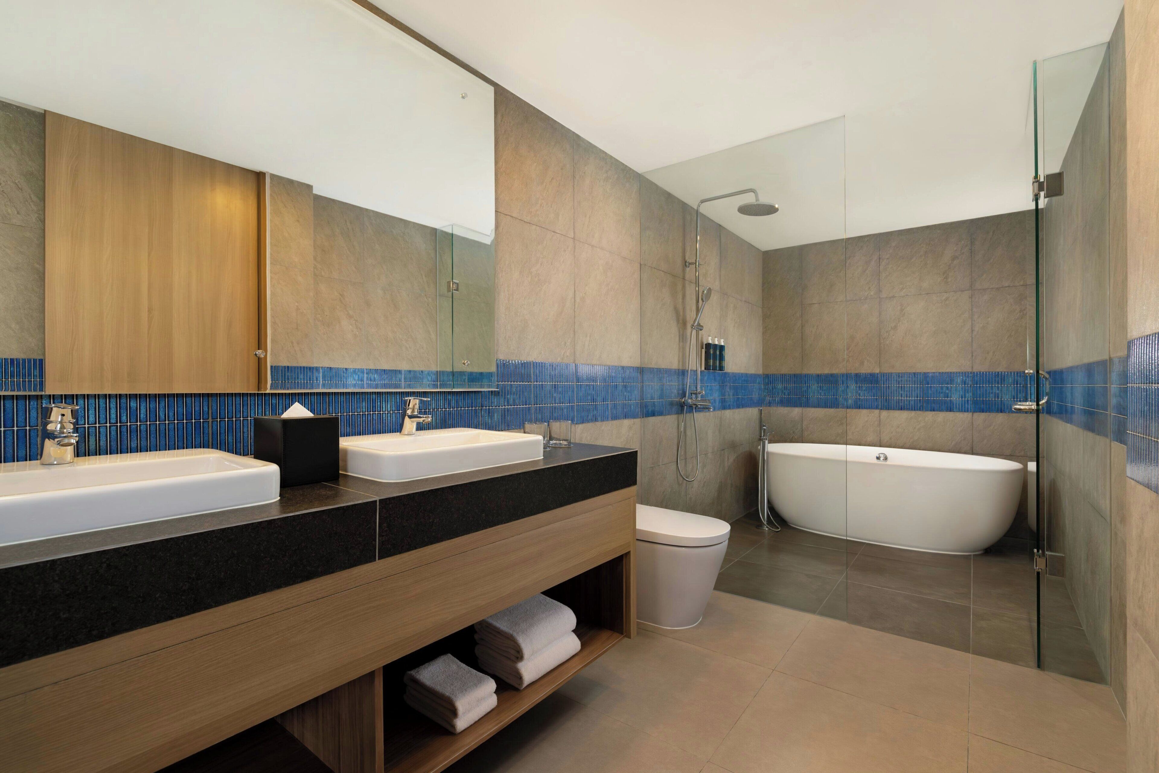 Un baño moderno con un espejo grande, dos lavamanos, una bañera y una ducha.