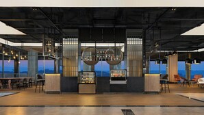 A modern bar area with a view of the cityscape, featuring a bar counter, shelves with bottles, and seating. - Four Points By Sheraton Pontianak (Pontianak)