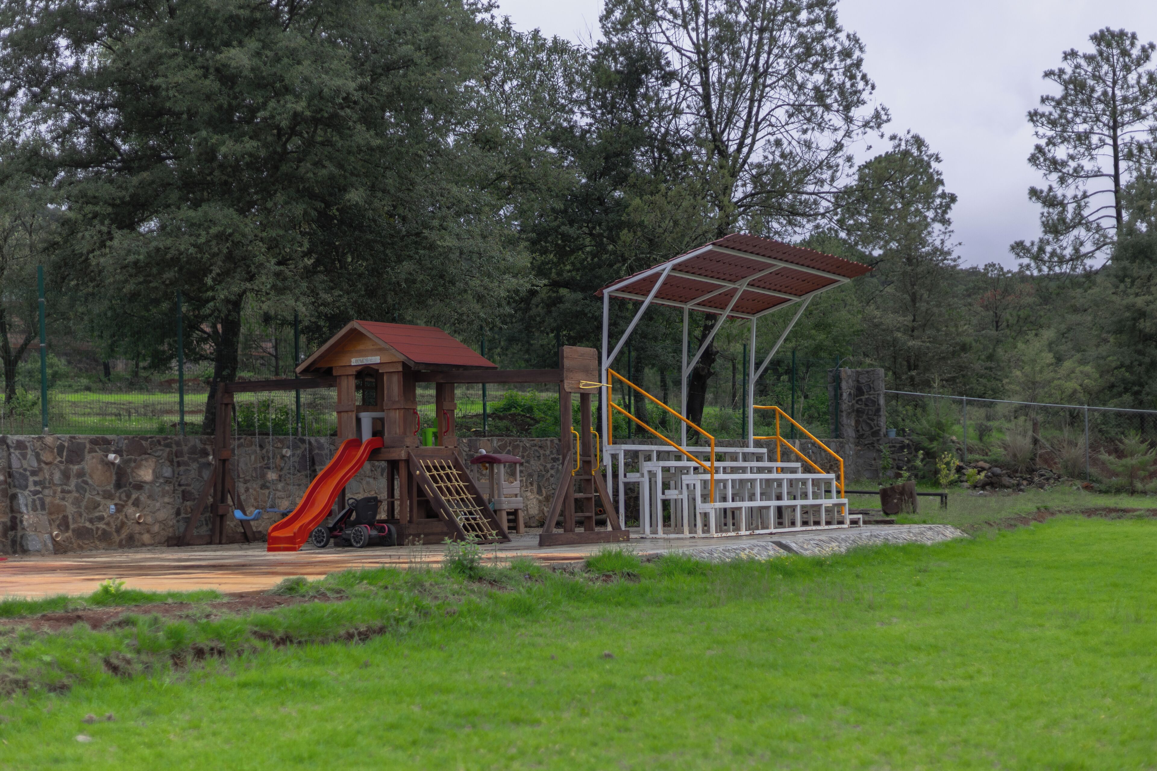 Une aire de jeux avec un toboggan, des structures d’escalade et un espace de jeux couvert.