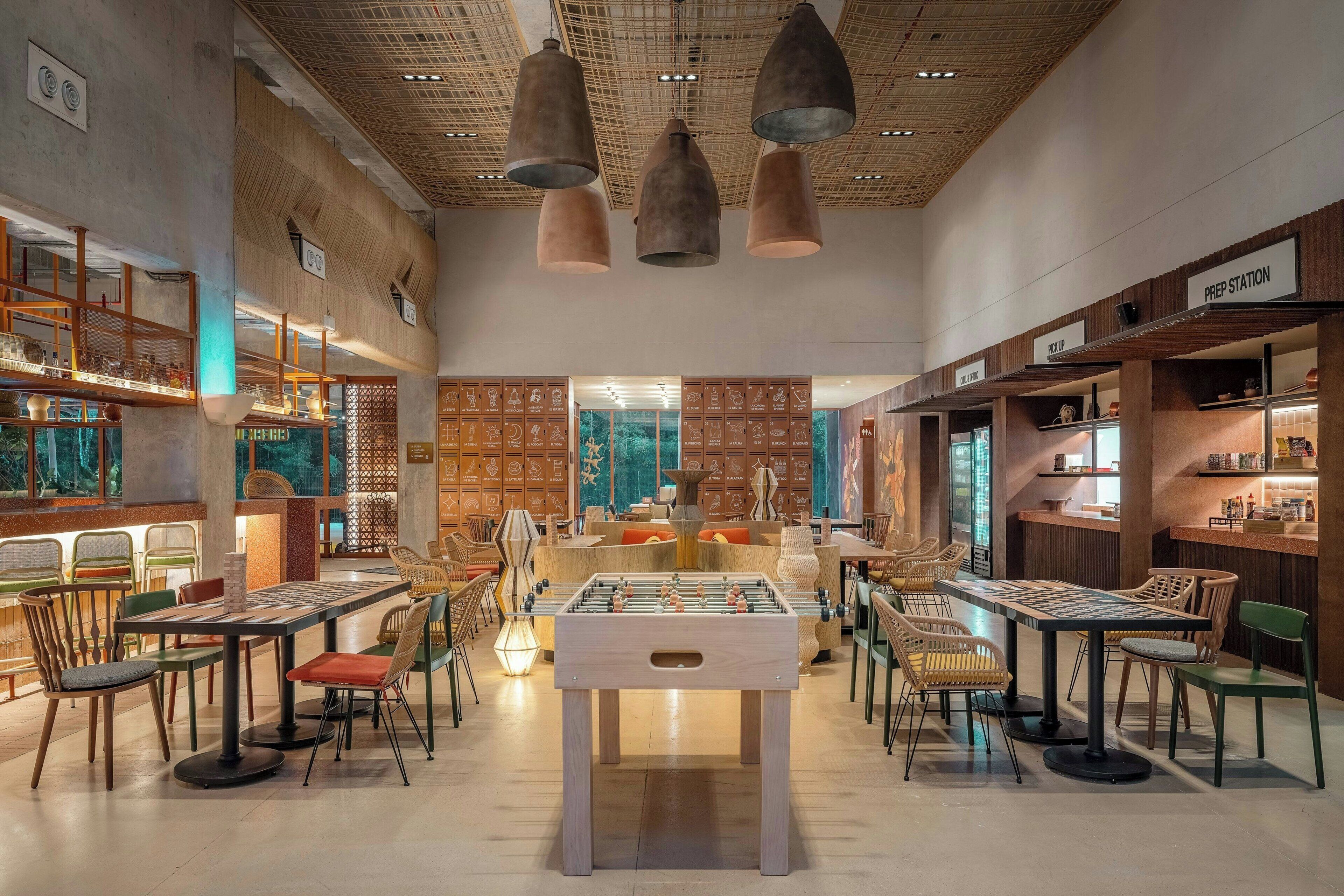 A restaurant with a foosball table, wooden furniture, and a modern ceiling design.