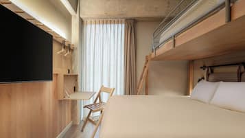 Une chambre avec un lit superposé, un téléviseur à écran plat fixé au mur, un bureau en bois et une chaise.