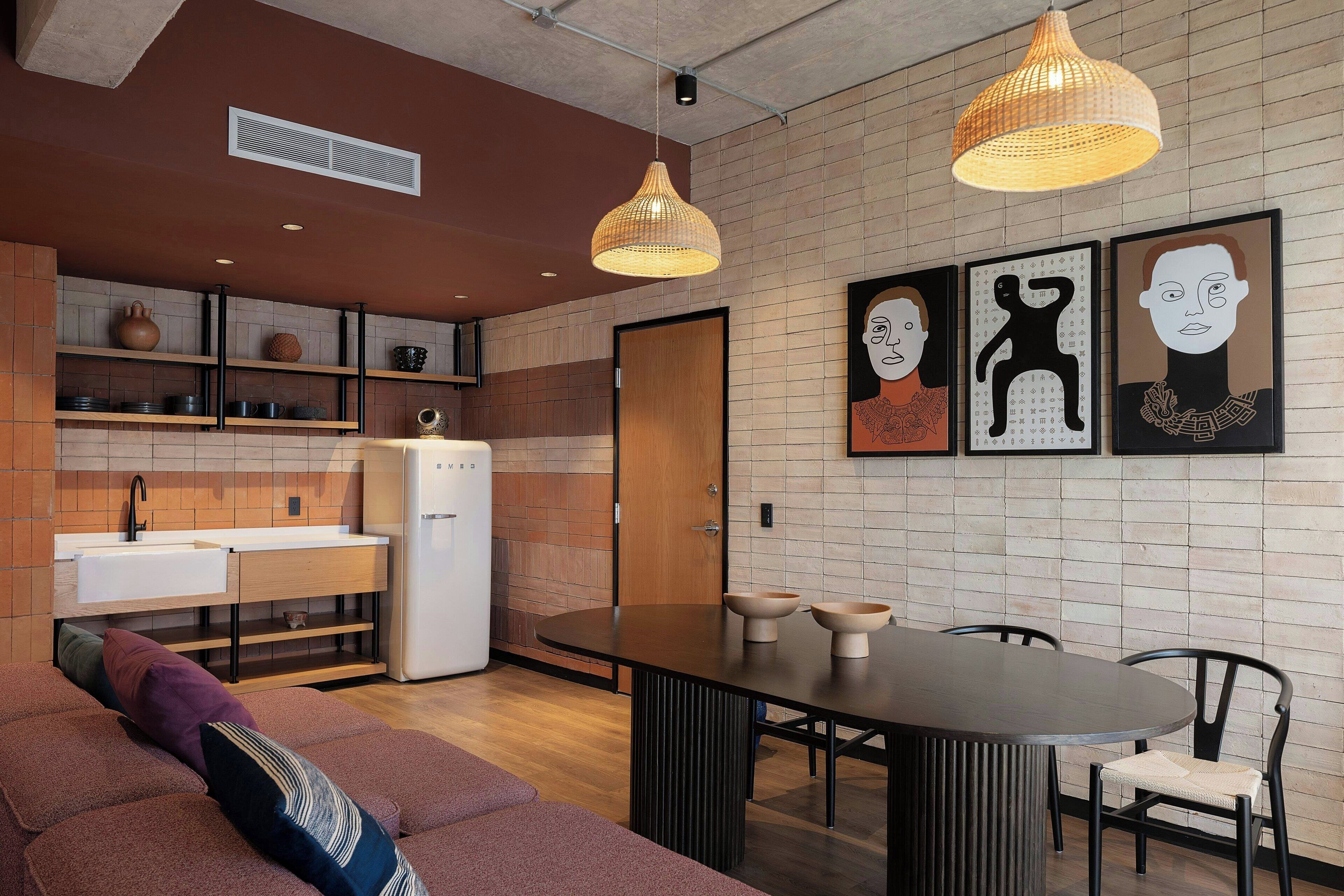 A modern kitchen with a dining area, featuring a round table, chairs, and a sofa with cushions.