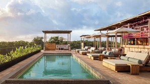 Un espace aménagé au bord de la piscine, comprenant une pergola, des chaises longues et des parasols.
