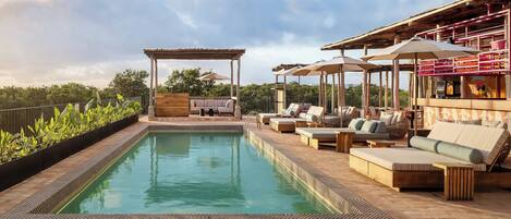A poolside area with a pergola, lounge chairs, and umbrellas.