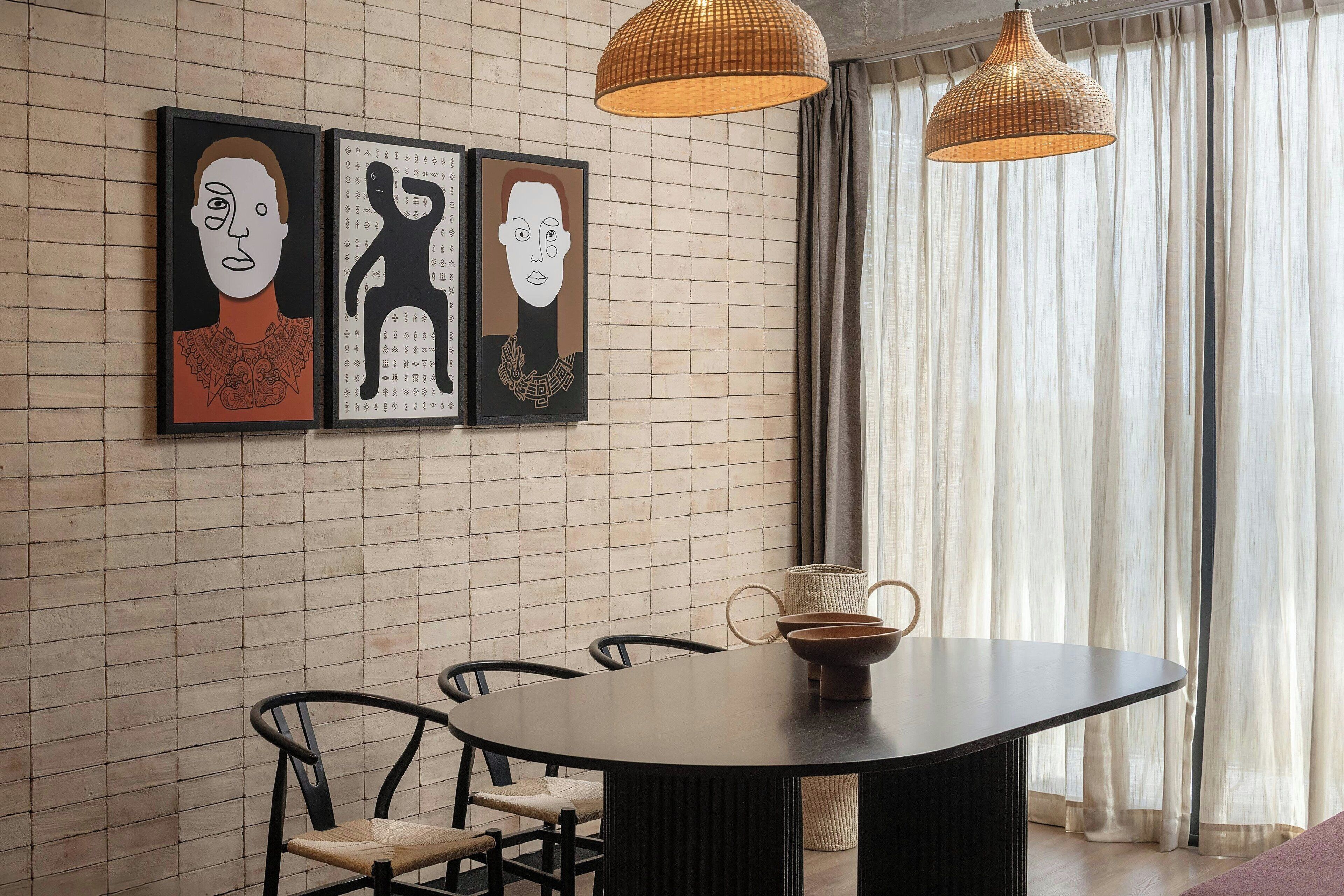 A dining area with a round table, chairs, and artwork on the wall.