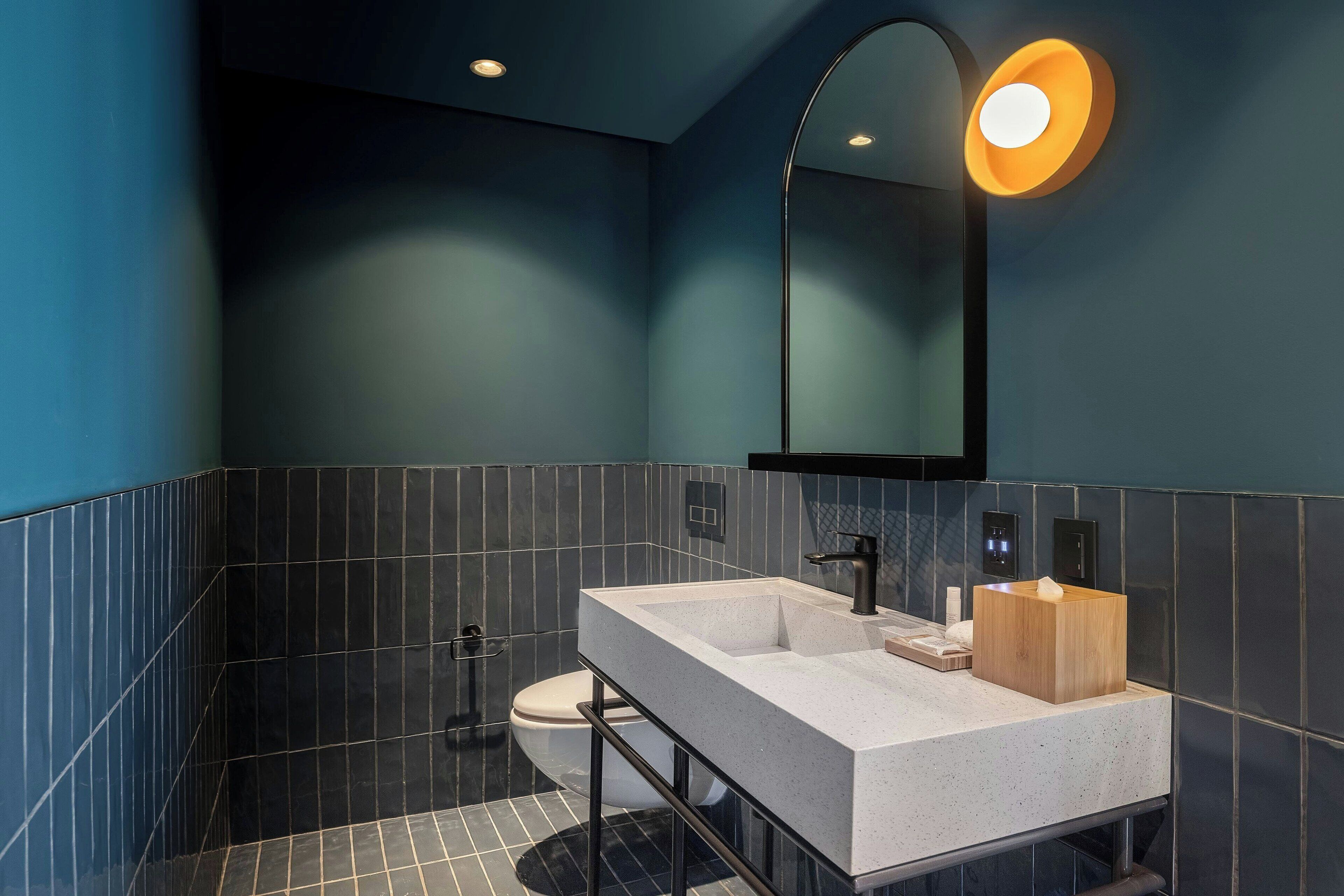 A modern bathroom with a large rectangular sink, a mirror, and a toilet.