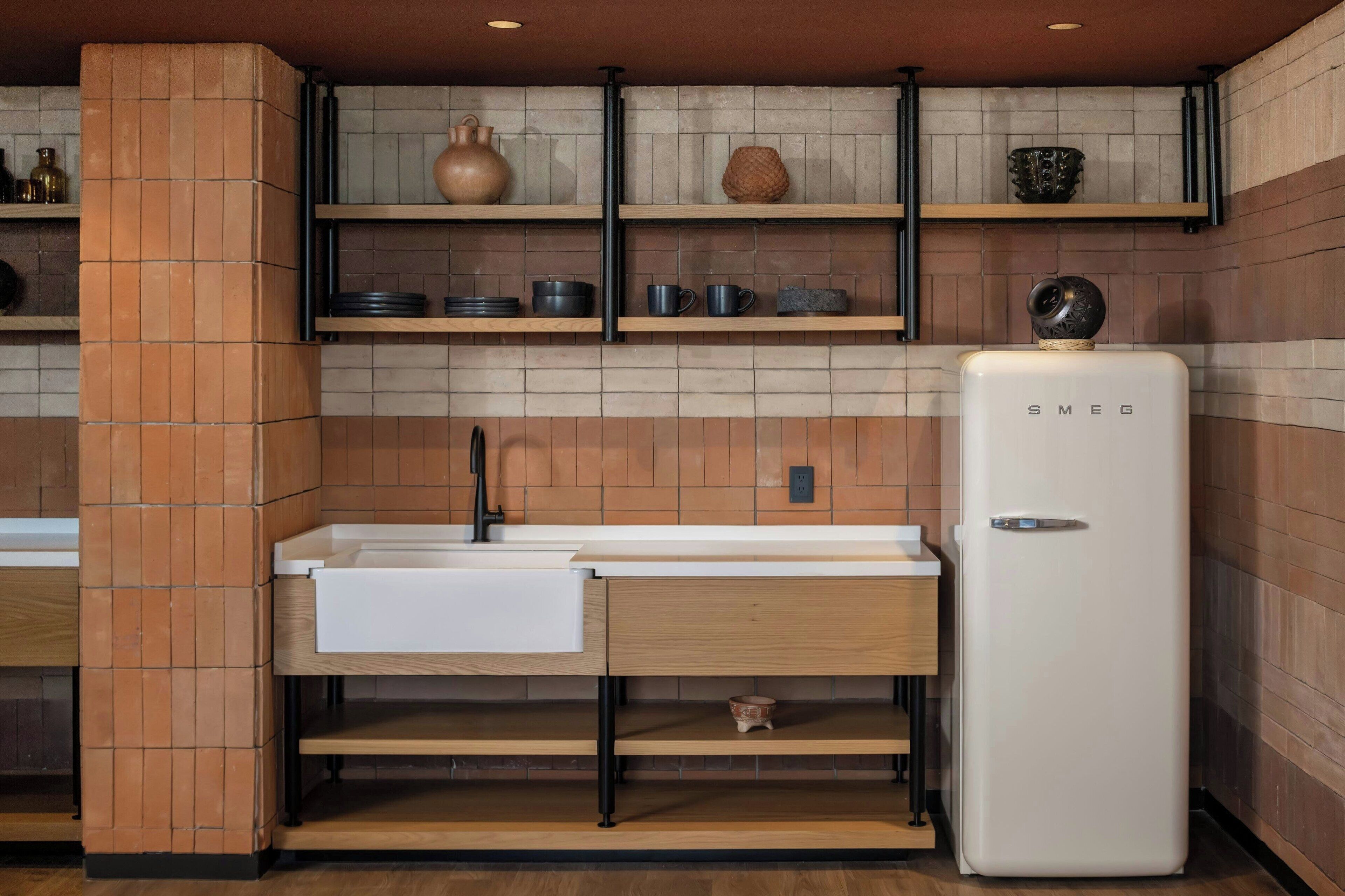A kitchen with a white countertop, a built-in sink, a white refrigerator, and shelves with kitchenware.