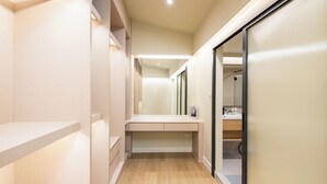 A narrow hallway with a wooden floor, a built-in bench, and a sliding glass door leading to a bathroom with a mirror and a sink. - Luxury 5BR Poolhouse & Theater - 2mins to BTS (Bangkok)