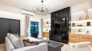 A modern living room with a sofa, coffee table, and a fireplace. - Luxury 5BR Poolhouse & Theater - 2mins to BTS (Bangkok)