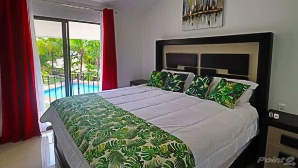 Un dormitorio con una cama grande, vista a una piscina y un cuadro en la pared.