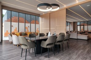 Un espace repas moderne avec une table en verre, des chaises grises et un séparateur en bois.