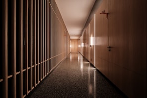 A corridor with wooden lockers and doors, a polished floor, and a neutral color scheme.