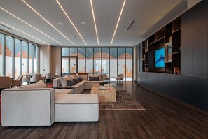 A modern living room with a sectional sofa, a coffee table, and a TV on a wall.