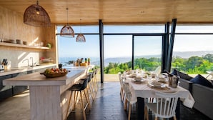 A modern kitchen with a large island, wooden accents, and a view of the outdoors. - Olas de Buchupureo - con vida de campo (Buchupureo)