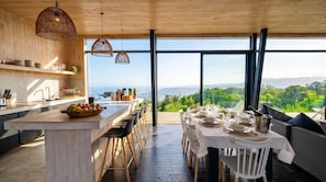 A modern kitchen with a large island, wooden accents, and a view of the outdoors.