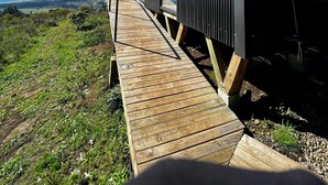 A modern building with a wooden deck leading to a large window, overlooking a coastal landscape. - Olas de Buchupureo - con vida de campo (Buchupureo)