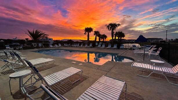 A poolside area with lounge chairs and a clear view of the sunset.