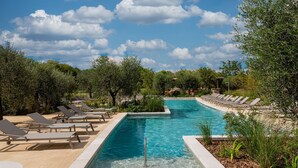 A rectangular swimming pool with clear blue water, surrounded by lounge chairs and greenery. - Séjour chic avec accès au spa + piscine (Baillargues)