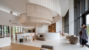 A spacious lobby with a central seating area, a wooden reception desk, and large windows offering views of the outdoors.