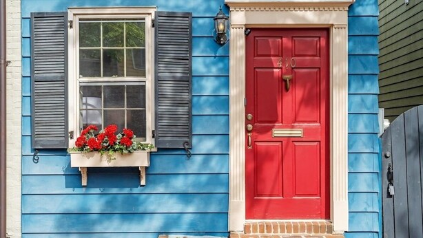 A house with a red door and a window with shutters.