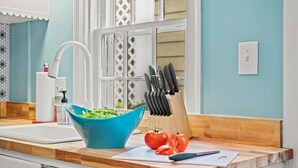 A kitchen with a blue bowl of salad, a cutting board with tomatoes, and a knife block.