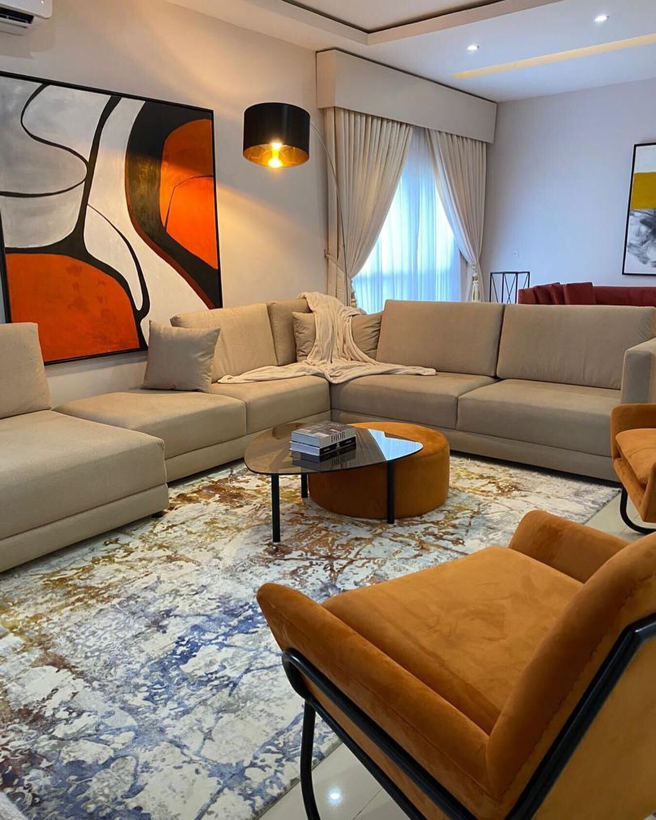 A modern living room with a sectional sofa, a round coffee table, and a large abstract painting on the wall.