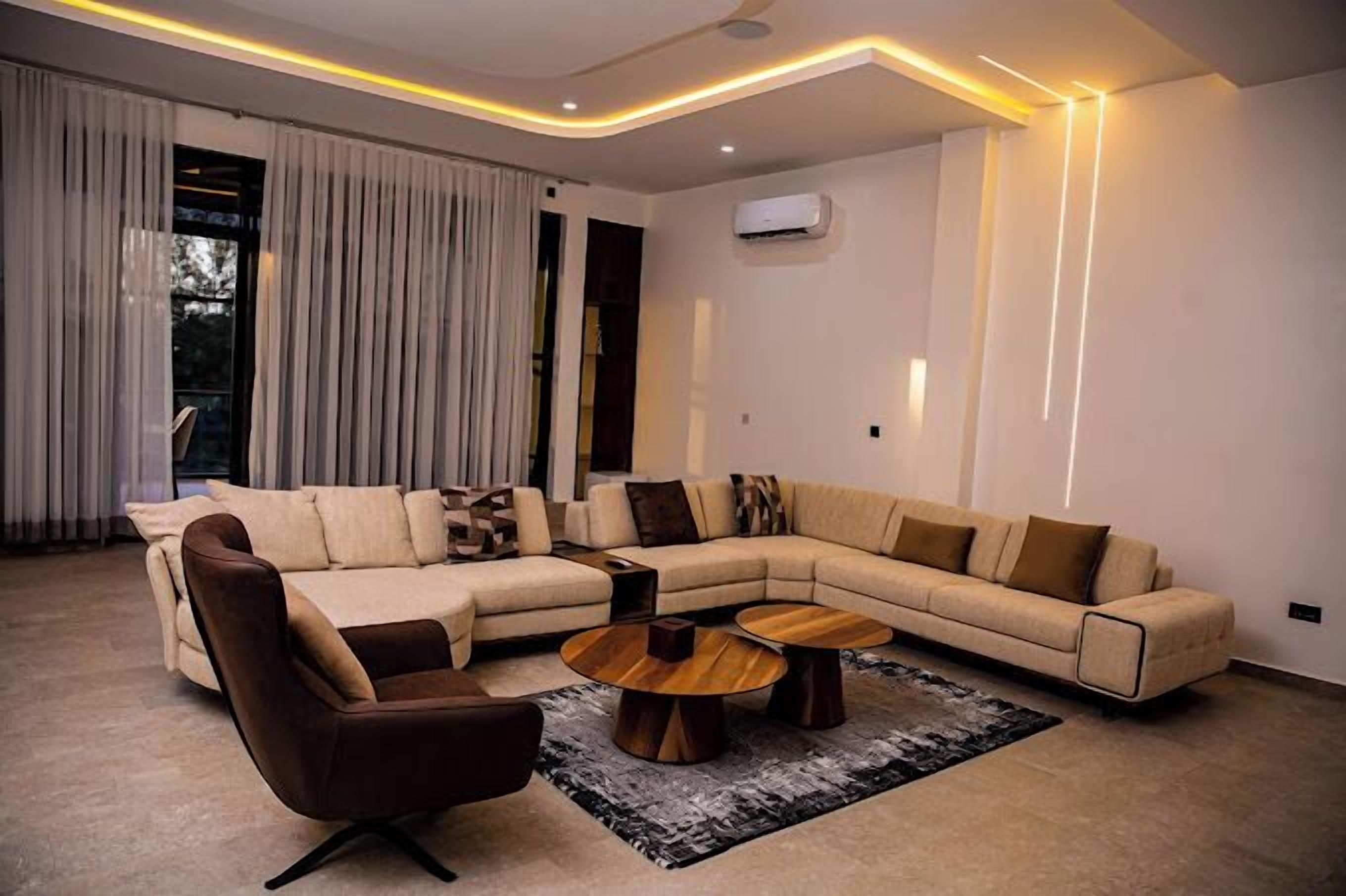 A modern living room with a sectional sofa, a brown armchair, and two wooden coffee tables.