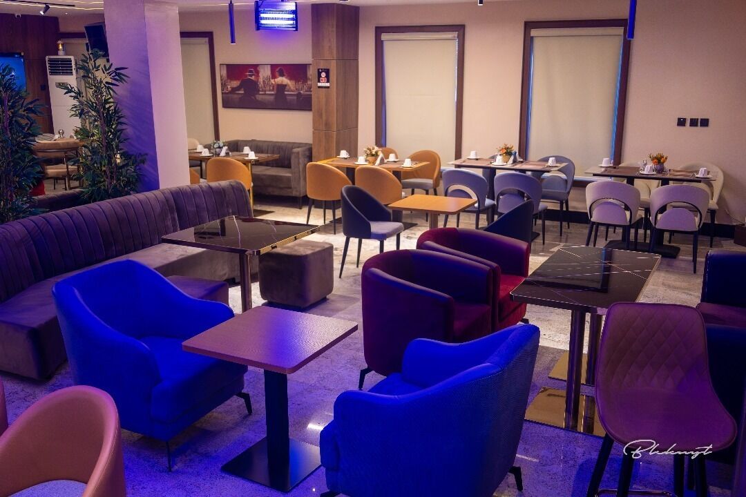 A hotel lobby with a mix of seating options including sofas and tables, a large plant, and a television mounted on the wall.