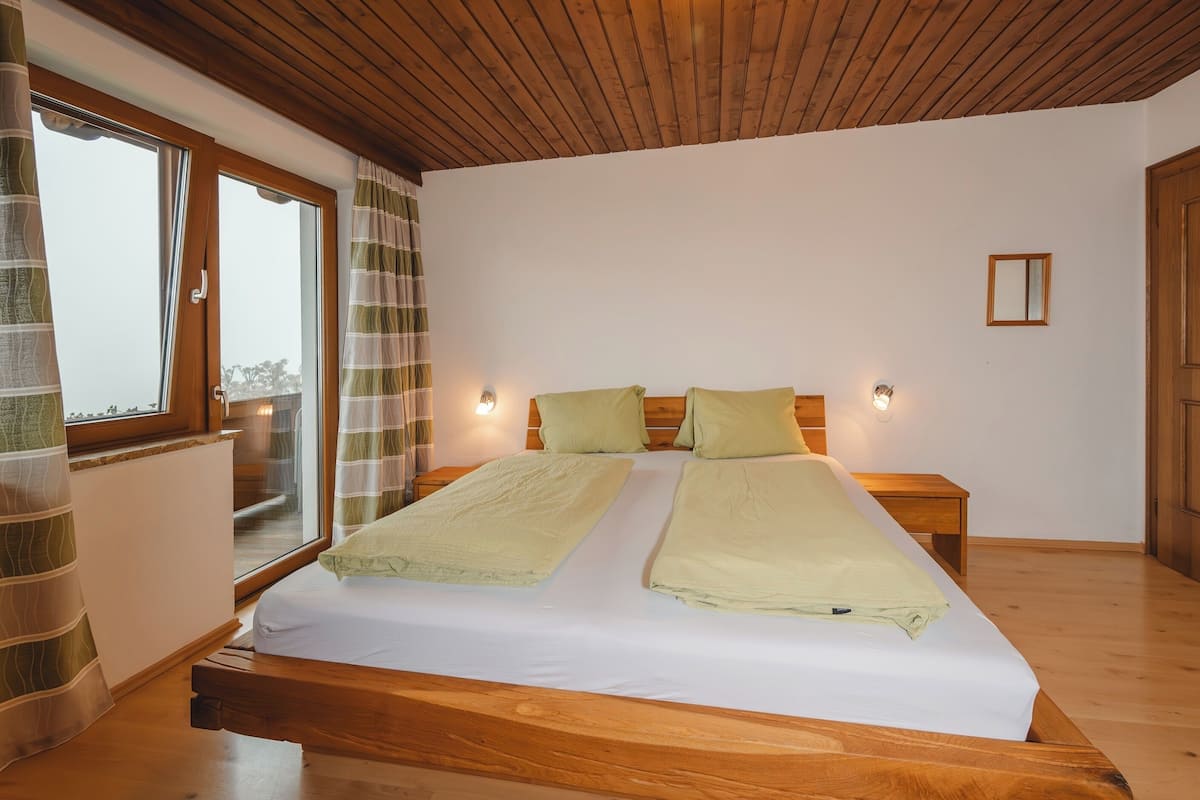 A double bed with two pillows, a wooden headboard, and bedside tables with wall-mounted lights.
