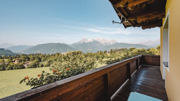 Un balcon doté d’une balustrade en bois, d’où l’on peut admirer un paysage montagneux.