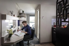 A modern office space with a desk, chair, and shelves with books and decorative items. - Student Only Walnut Gardens (Exeter)