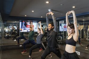 A group of people exercising in a gym with mirrors and exercise equipment. - Student Only Walnut Gardens (Exeter)
