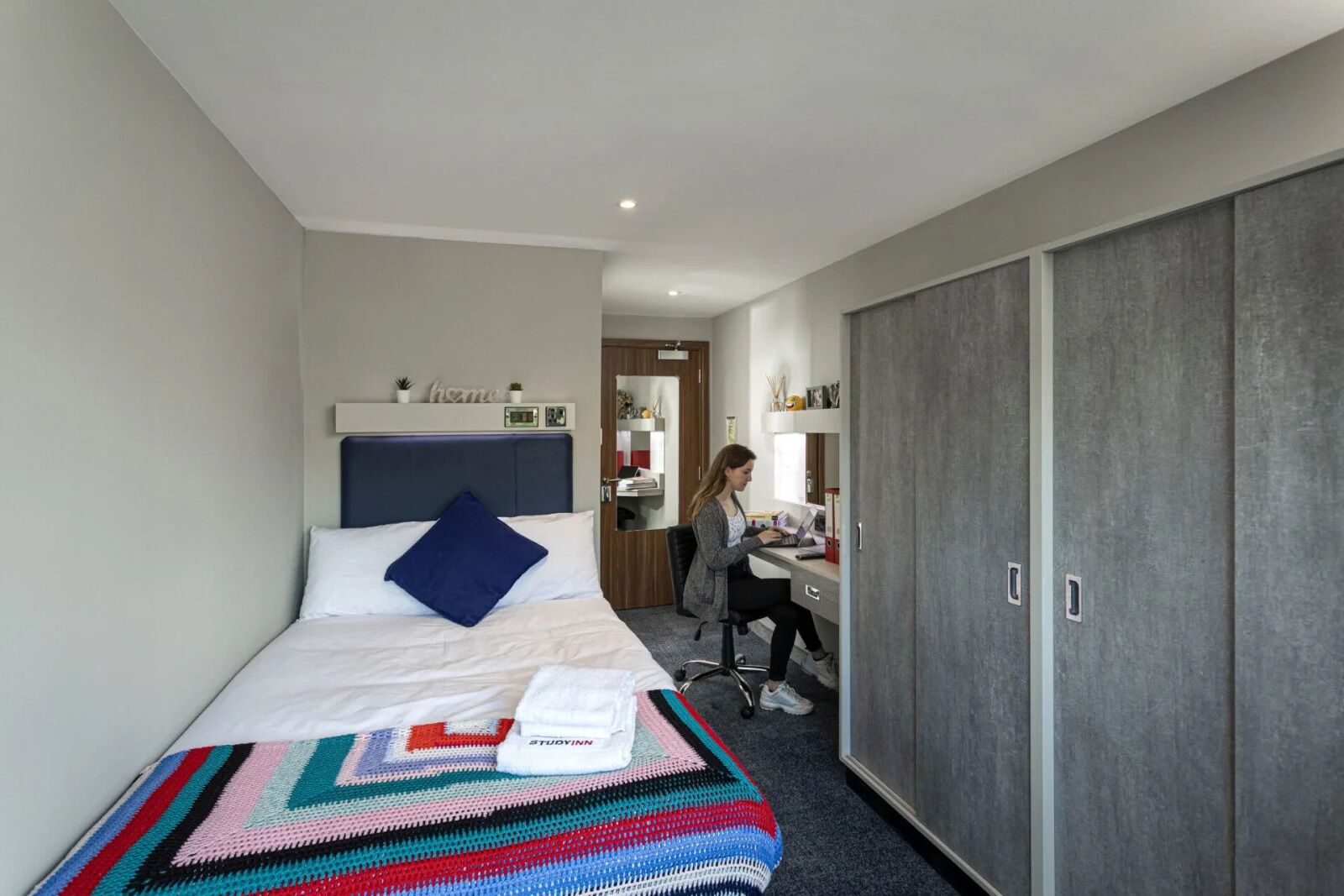 A hotel room with a bed, a desk, and a wardrobe.
